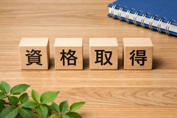 資格取得を表す木製ブロックが机に並び学習やスキルアップを象徴するイメージ