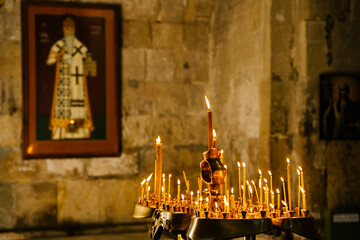 Candles in a Christian Orthodox church background. Flame of candles in the dark sacred interior of the temple
