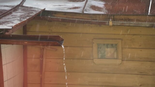 summer rain, a downpipe under the roof of a house with a stream of water during a downpour