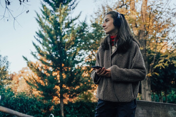 Peaceful Woman Relaxing and Listening to Music in Autumn Park