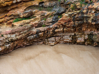 Layered rock formation and sand on a beach in Nazar&eacute;