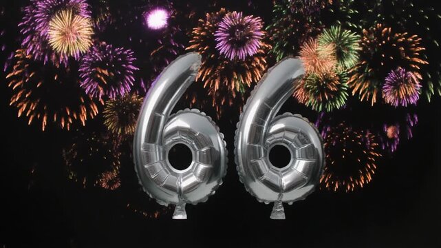 Silver balloon number 66 with fireworks in the background. Festive scene for birthday or anniversary party