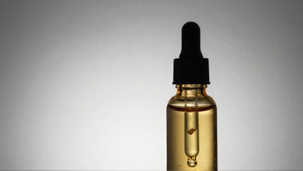 Dropper bottle with golden liquid drop forming