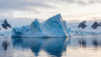 Iceberg floating in calm sea with snowy mountains