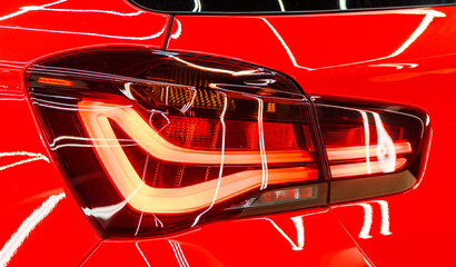 LED turn signal in the rear brake light of the red car. Modern car lantern, close-up. Detail on the rear light of a red glossy car. Close-up of a modern red automobile with LED red taillights.