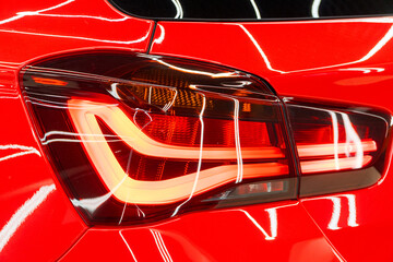 LED turn signal in the rear brake light of the red car. Modern car lantern, close-up. Detail on the rear light of a red glossy car. Close-up of a modern red automobile with LED red taillights.