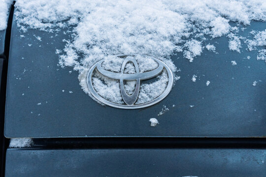 Toyota logo covered with snow. A gray Toyota Land Cruiser covered with snow is parked on the street. Snow-covered Land Cruiser 80 (J80) logo on the trunk lid in winter. Japanese SUV car. 