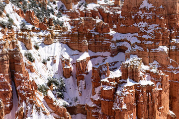 Rugged snow-covered cliff with hoodoos at Bryce Canyon National Park in Utah. Lit with the afternoon sun, just after a winter storm. 
