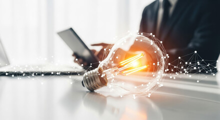 Illuminated light bulb symbolizing a new idea, with a person in the background using a digital tablet in a bright, minimalist workspace. Represents innovation, business and technology.