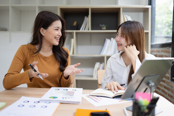 Obraz premium Two asian businesswoman using digital tablet and talking about business with analyzing financial charts in the modern office.