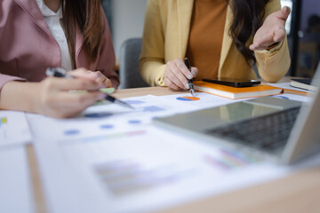 Two asian businesswoman using digital laptop and talking about business with analyzing financial charts in the modern office.