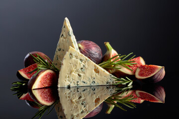 Blue cheese with fresh figs and rosemary on a black background.
