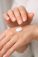 A woman is applying lotion to her hands. Concept of self-care and relaxation, as the woman takes the time to pamper herself. The lotion bottle is positioned in the middle of her hand