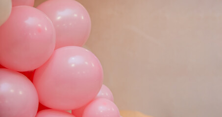 Soft pastel balloon decoration with pink balloons on beige background. Minimal party backdrop with copy space for birthday, baby shower, wedding or festive design.
