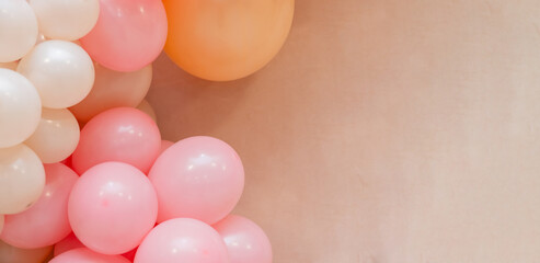 Soft pastel balloon background with pink, peach and white balloons on beige wall. Minimal festive decoration with copy space for birthday, baby shower, wedding or celebration design.