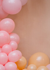 Soft pastel balloon decoration with pink balloons on beige background. Minimal party backdrop with copy space for birthday, baby shower, wedding or festive design.