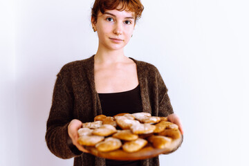 young woman holding gingerbread cookies on wooden round board