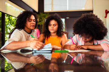 Three Black women studying together at a table with notebooks and pens, focusing on their work and learning.