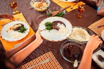 Family enjoying a traditional Brazilian feijoada meal with rice, beans, and farofa served at a table.