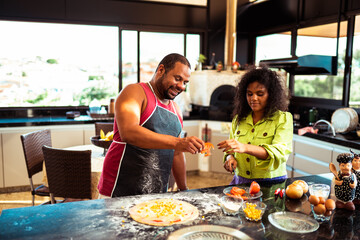 Happy couple preparing homemade pizza together in a modern kitchen.