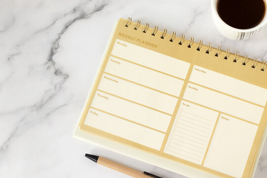 Weekly planner with daily notes and to do list blank page with coffee cup on white marble background. Top view. Personal resolutions, aspirations, goals, and time management concept. - Powered by Adobe
