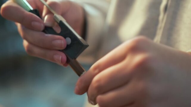 Close-up of a young woman adjusting the screw on a violin bow, preparing for a music practice session. Soft daylight and cozy atmosphere.