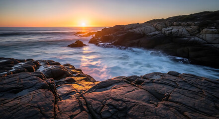 A serene rocky coastline at sunset with waves crashing against the shore