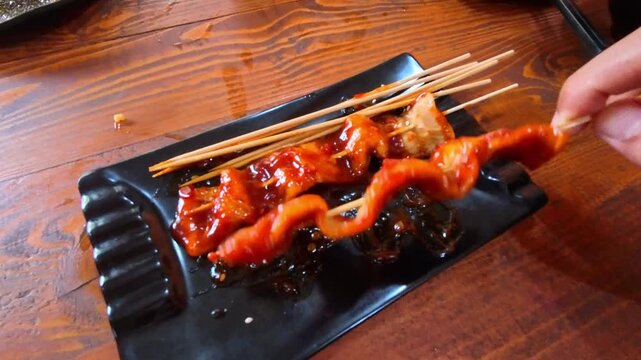 Clip of a hand picking up a dish of fried Korean fish cake or spicy odeng on a bamboo skewer. Videography of Korean fish cake gourmet in 4K HD Resolution