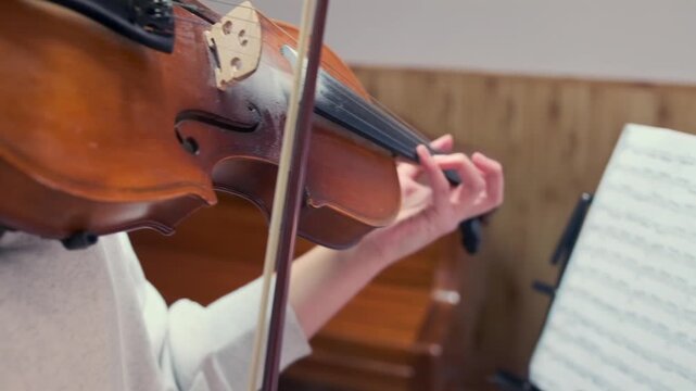 Close-up of a focused young violinist reading sheet music while playing. She is sight-reading during home practice or music lesson, showing discipline, skill, and strong connection to her instrument.