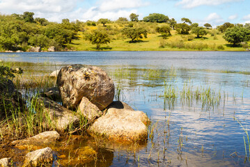 Stones on the shore of a calm lake during an autumn day. Clean natural background, no people.