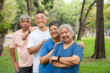 Four older adults enjoy a cheerful moment together in a lush outdoor setting. Their smiles and relaxed poses highlight themes of friendship, active aging, and joy of social connection in later life.