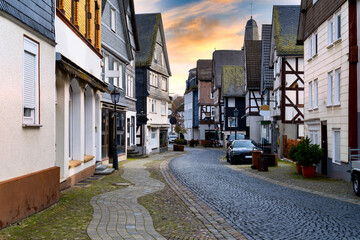 Bad Laasphe, Siegen-Wittgenstein, historic old town street with timber houses, paved road, shop windows and autumn trees in background at sunset
