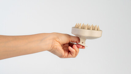 A hair comb used for massaging the scalp while washing hair, held in the hand against a white background.