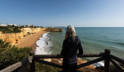 girl, Yellow rocks and cliffs on the sandy beach. A cove by the sea, Our Lady of the Rock, Praia Nova, Lagos. Algarve, Portugal
