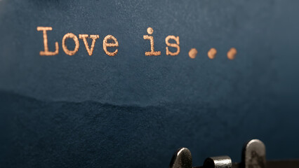 Vintage Typewriter Text Reading Love Is on Textured Blue Paper Background