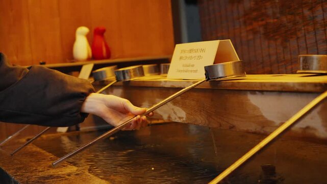 Person performing purification ritual at japanese shrine