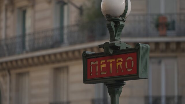 PARIS, FRANCE - DECEMBER 16, 2025 - Metro sign post displaying direction to subway while blurring Paris architecture in background