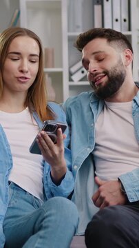 Young couple woman and man smiling looking at smart phone. Boy and gir shopping on internet, watching funny videos, use social media, streaming service. Slow motion.