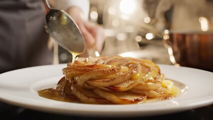 Chef carefully pours golden sauce over beautifully arranged caramelized apple dessert, fine dining