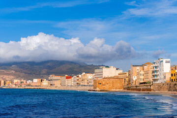 Obraz premium beautiful blue landscape of sea coast embarkment in a city with beach and mediterraneran buildings and modern houses. Panoramic view of blue sea waves and beautiful mountains on background