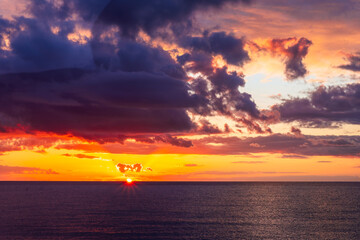 Dramatic seascape of sunset or sunrise sky with clouds during morning or evening. Dramatic sunset over the sea with orange clouds and sun above ocean water