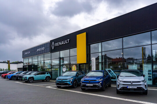 Modern Renault car dealership with glass facade and new cars parked in front of building exterior