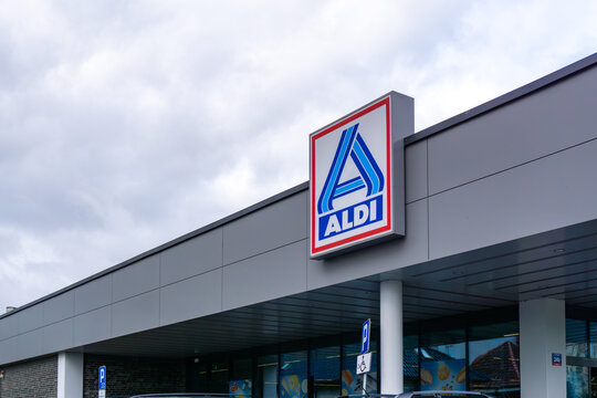 Aldi logo on modern grocery store facade near parking area in urban surroundings