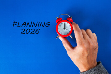 Hand holding alarm clock with planning 2026 text