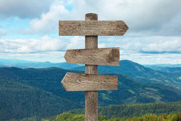 Wooden signpost with arrows pointing in different directions in mountains