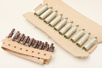 Old capacitors in paper tape. Aluminum capacitors on a white background. The electronic components are in their original packaging.