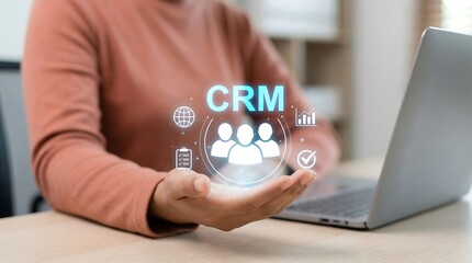 A person presents a glowing crm interface with icons representing management data and connectivity above an open laptop high quality