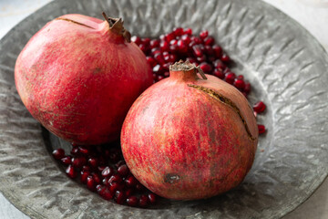 Whole Pomegranates and Seeds on Metal Plate