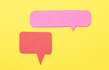 Pink red blank cut out paper speech bubbles with copy space for text on yellow background, flat lay top view conceptual conversation backdrop
