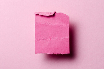 One single torn ripped wrinkled crumpled blank paper note with drop shadow, folded edge and copy space for text on pink background